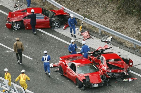 Police officers investigate wrecked luxury cars at the site of a traffic accident on the Chugoku Expressway in Shimonoseki