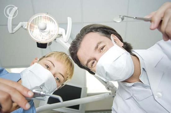 Dentist and assistant leaning down to work on patient